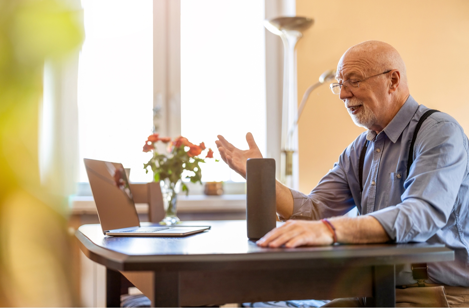 Senior using a smart speaker and laptop for easier handsfree communication when talking to others