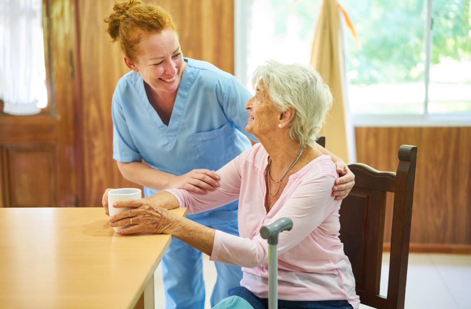 A senior care worker checks in on someone during their morning coffee.