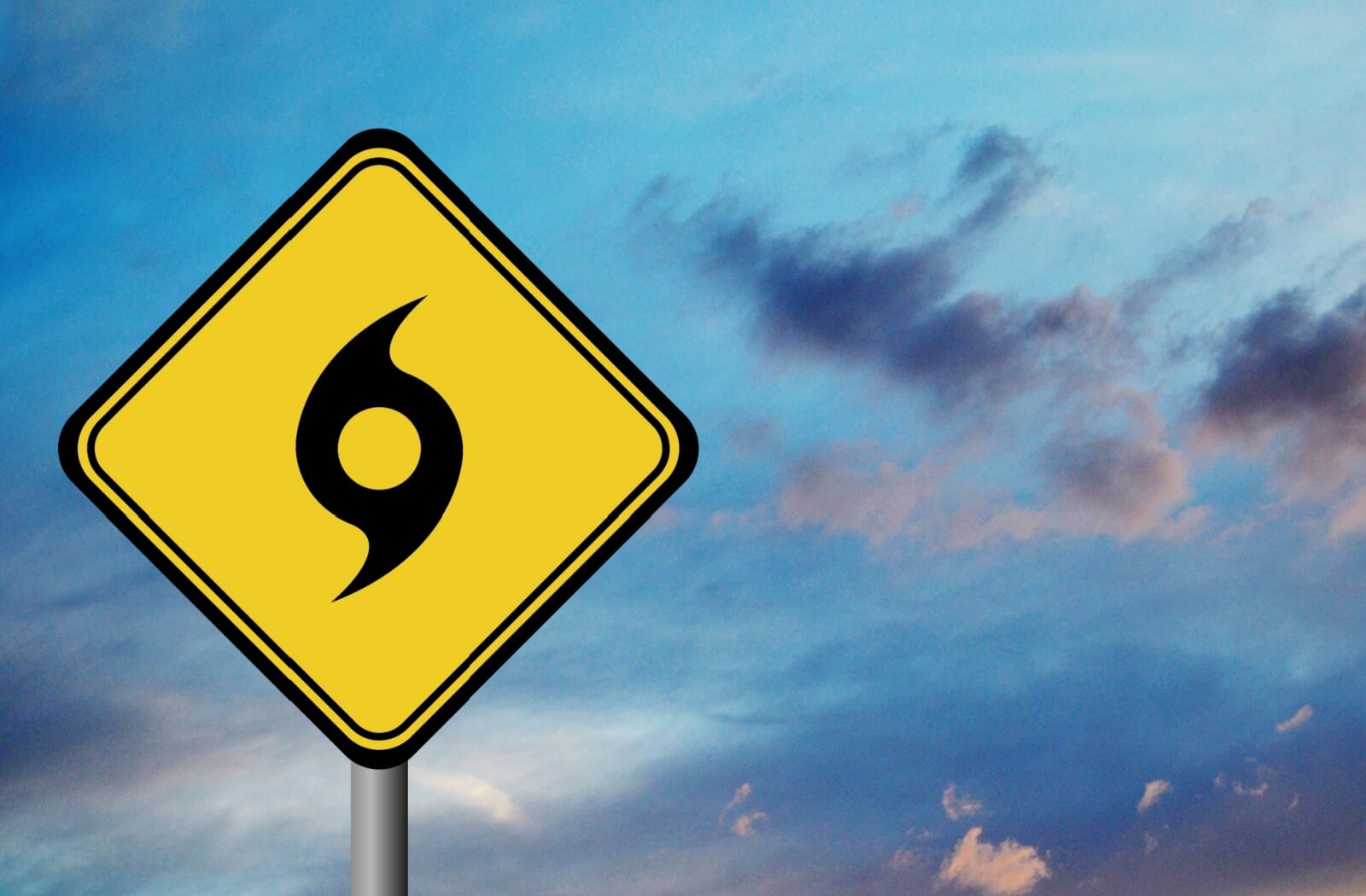 A yellow hurricane season plain in the foreground against a darkening, stormy sky